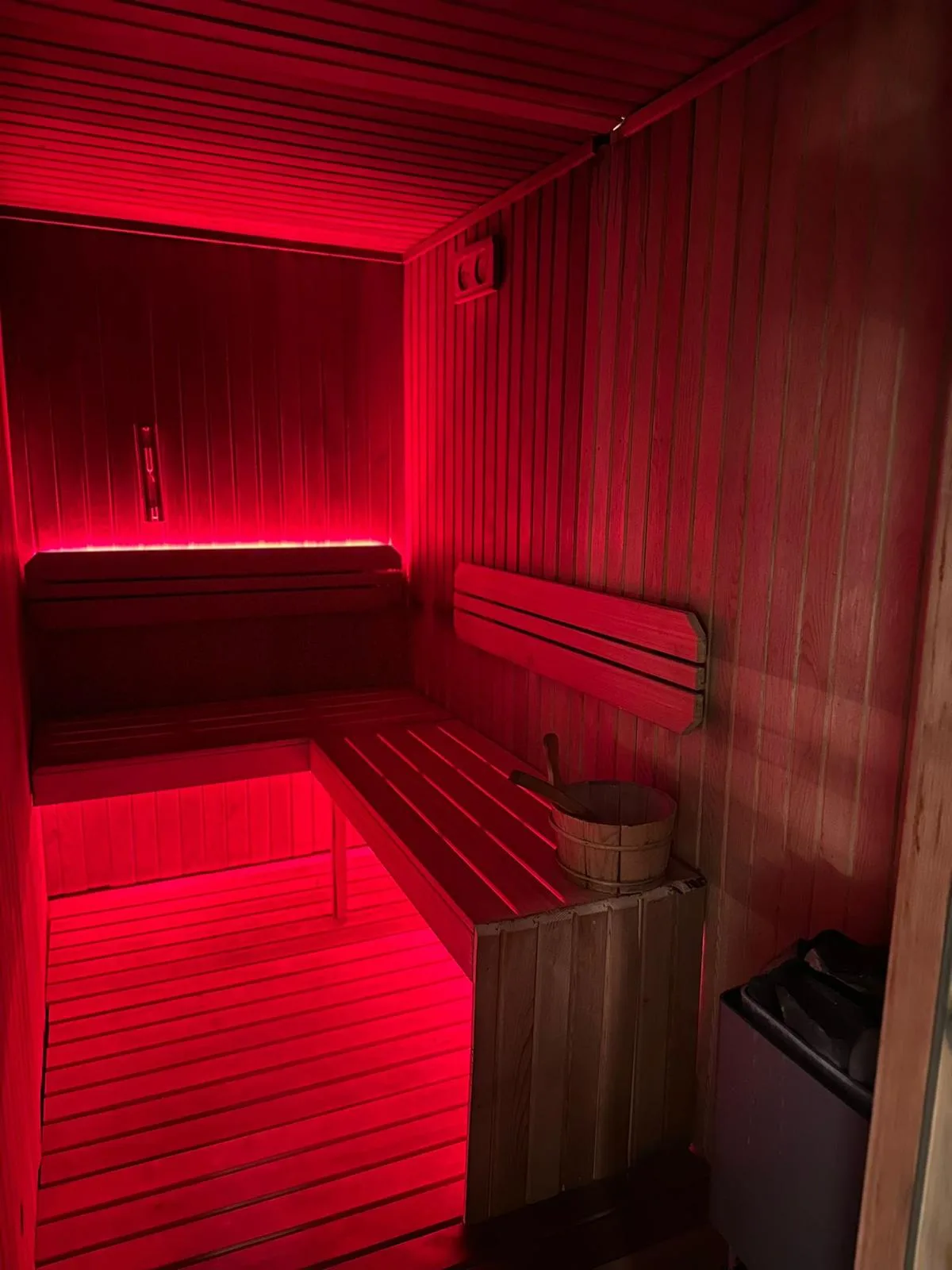 Spa Sparadise saunasında ahşap oturma alanları ve kırmızı aydınlatma